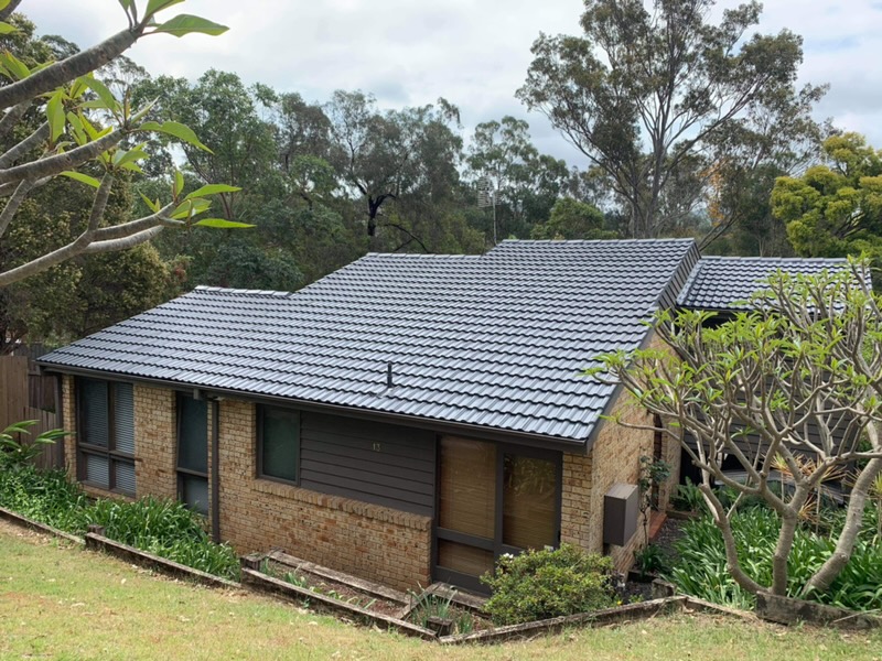 The same home after roof restoration, with the tiles cleaned and repainted in a uniform charcoal finish