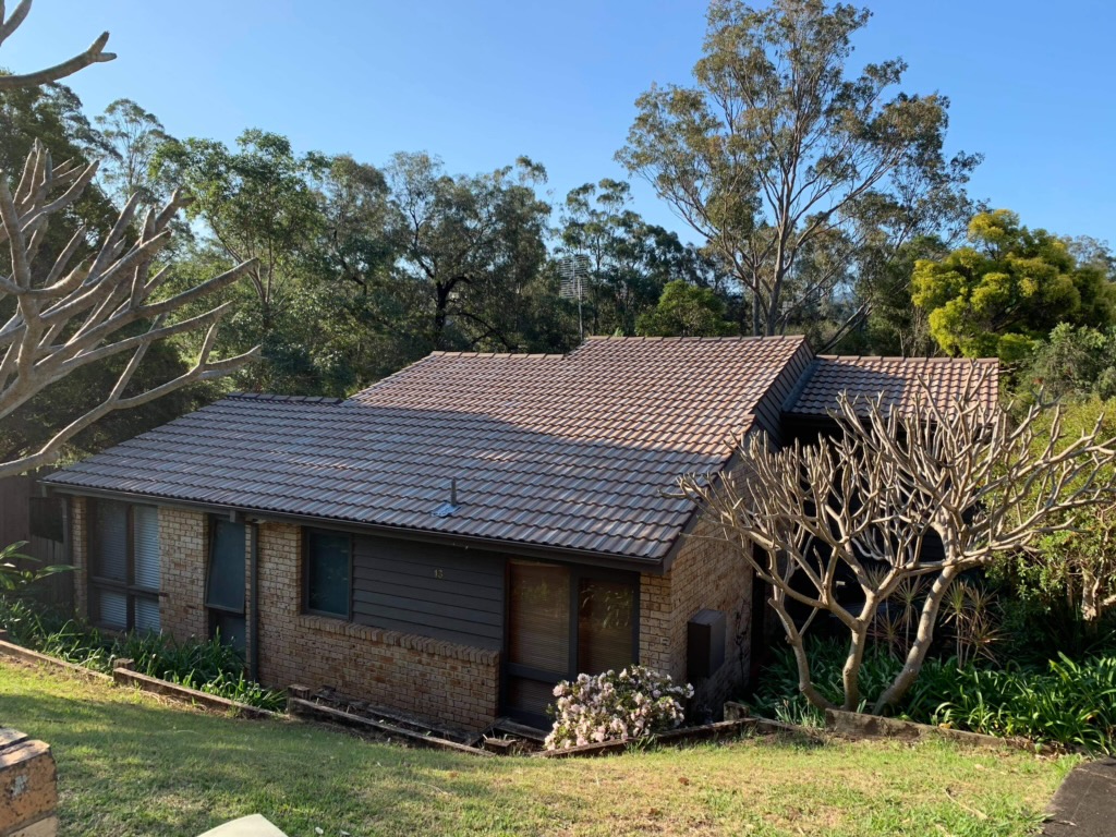 Brick home with faded, patchy terracotta roof tiles before restoration