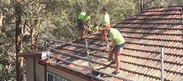 Roofer working safely on a pitched tiled roof with correct footing
