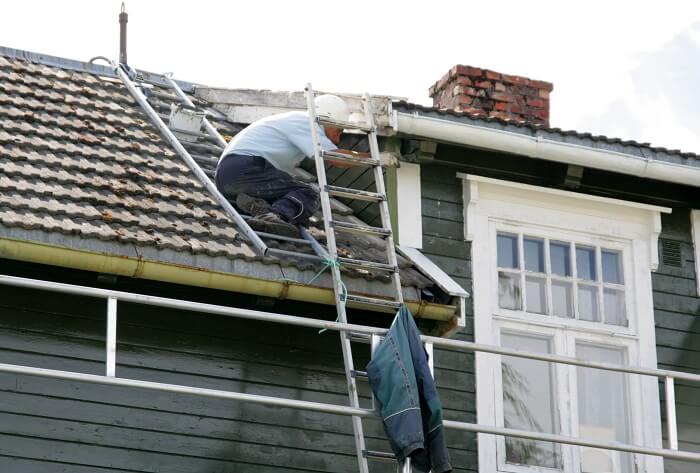 A man painting roof of a house